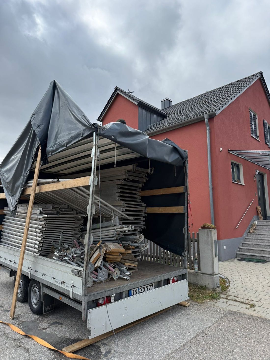 Gerüstanhänger vor dem fertig gestrichenen roten Wohnhaus