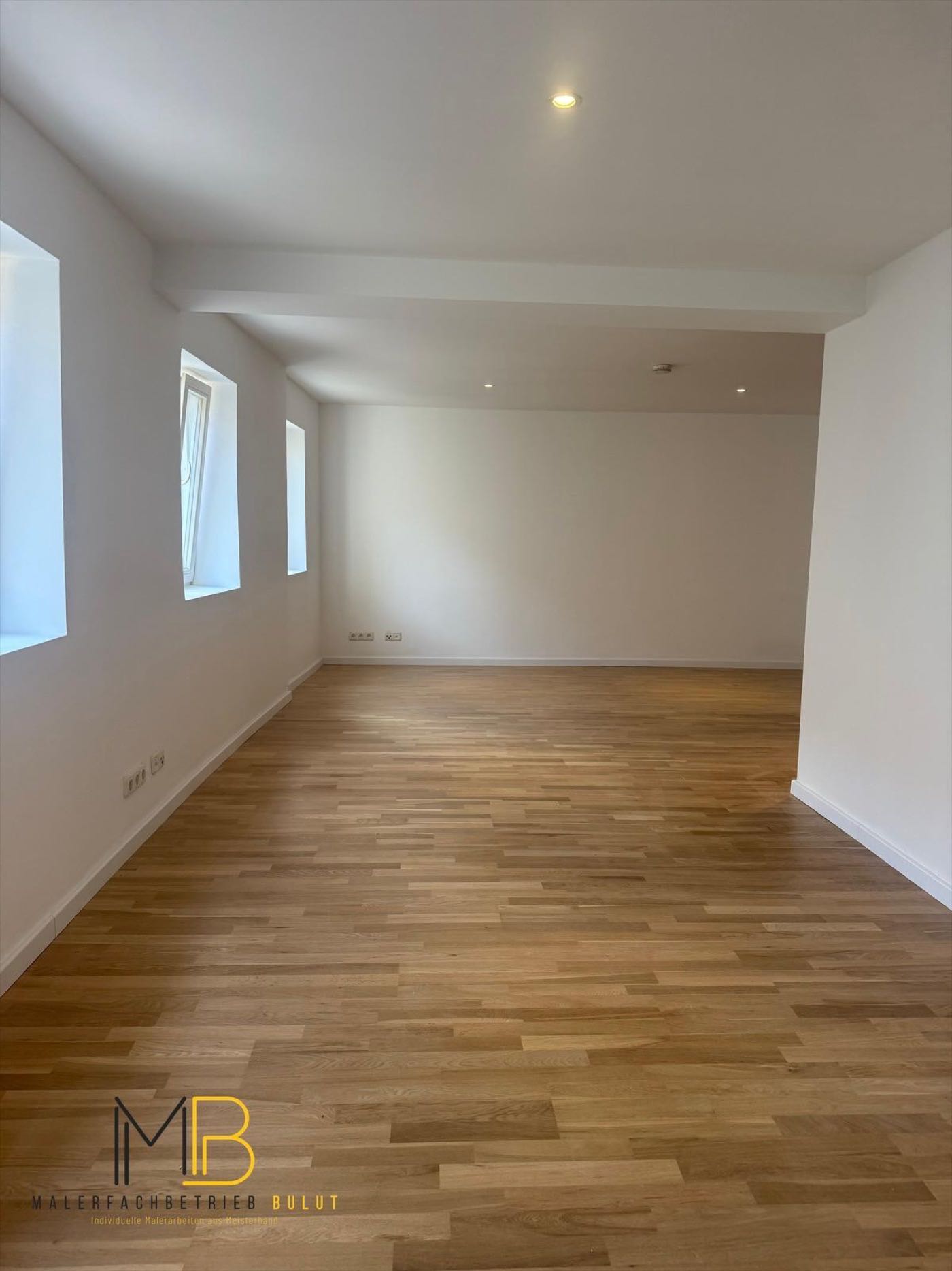 Renovierter Wohnraum mit weißen Wänden, hellem Parkett und großzügiger Fensterfront