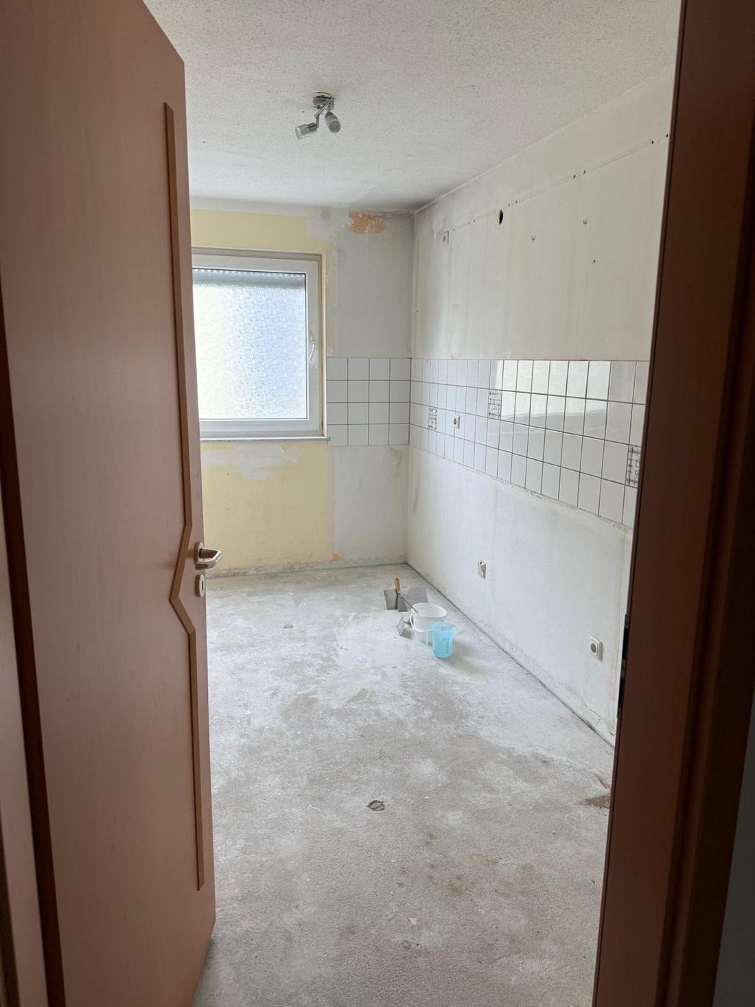 Küche im Rohzustand mit altem Fliesenspiegel und unbehandeltem Estrich